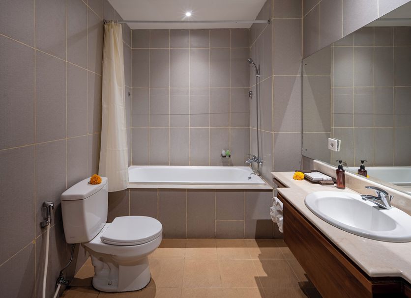 Pertiwi Bisma 1 Ubud bathroom with bathtub, toilet, sink, and large mirror