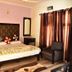 Hotel Vishla Palace in Rishikesh guest room with double bed, armchair and window curtains