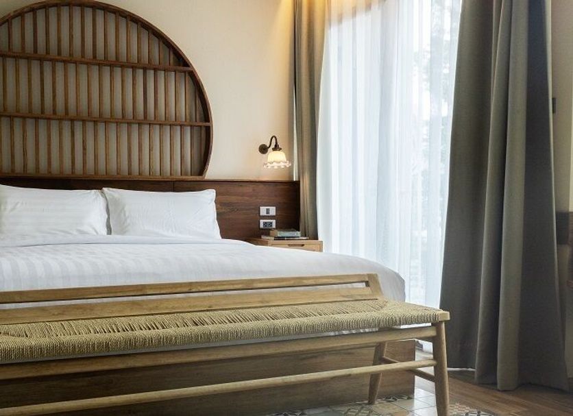 Tints Of Blue Hotel Bangkok room with king bed, round headboard, bench, and window seating