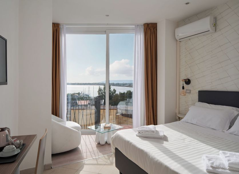 Hotel Centrale Siracusa guest room with bed, balcony, and sea view through sliding glass doors