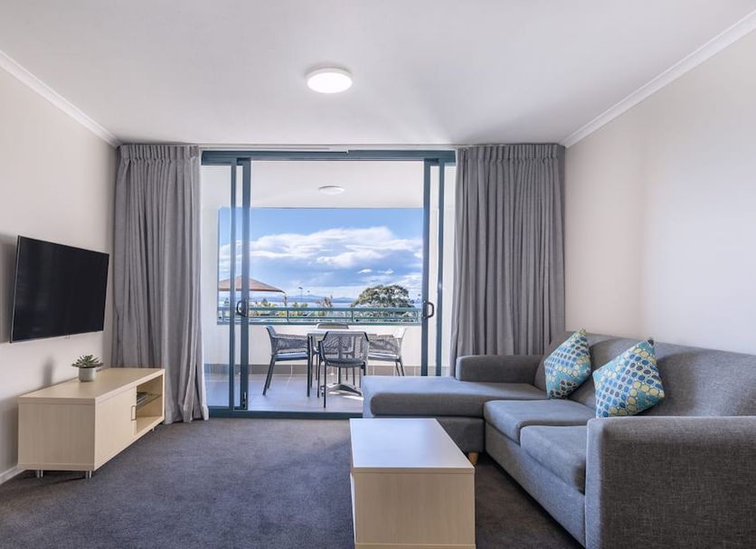 Landmark Resort Nelson Bay living room with sofa, TV, and balcony ocean view