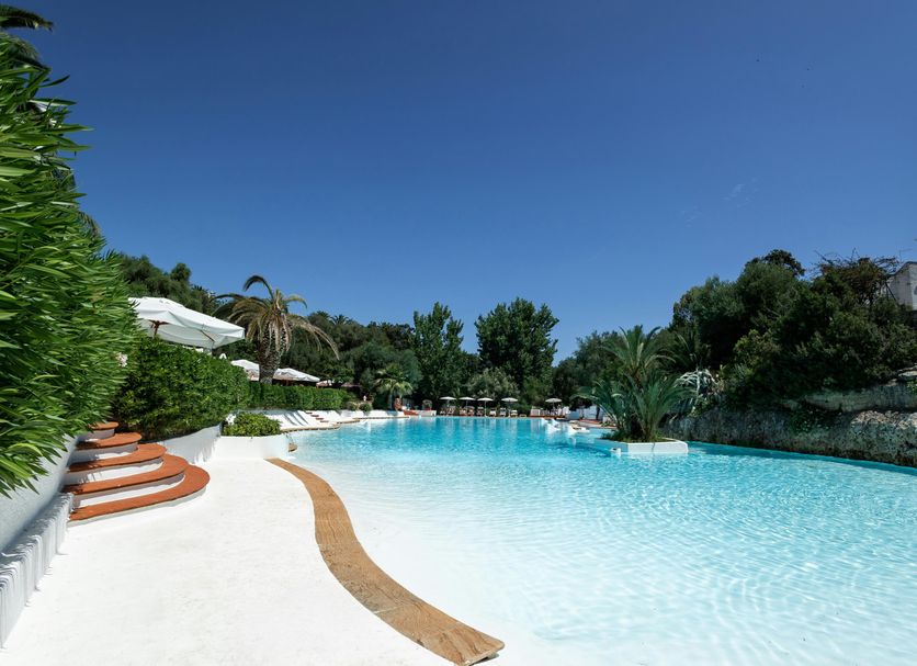 Ostuni a Mare in Ostuni featuring a curving outdoor pool with lounge chairs and lush greenery
