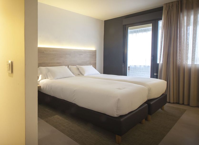 Hotel A Pamplona room with twin beds, bathroom vanity, and window view in Pamplona
