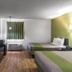 Motel 6 Augusta Ks room with two beds, wall-mounted TV, window, and wood-look flooring in Augusta
