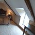 Au Pied Levé in Trévron attic guest room with wooden bed, sloped ceiling and skylight