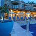Casa Lisa in Acapulco with stone terraces, lit patio seating, and a pool at dusk