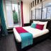 Hotel Peyris Opera in Paris guest room with striped accent wall, double bed, and balcony doors