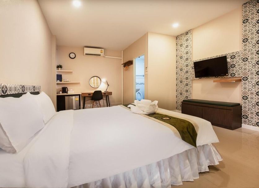 The Loom Rangsit in Pathum Thani: guest room with bed, desk, TV, and patterned accent wall