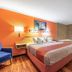 Motel 6 Gatlinburg Smoky Mountains guest room with king bed, orange accent wall, and soaking tub