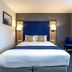 Days Inn by Wyndham London Stansted Airport guest room with double bed and blue accent wall in Bishop's Stortford