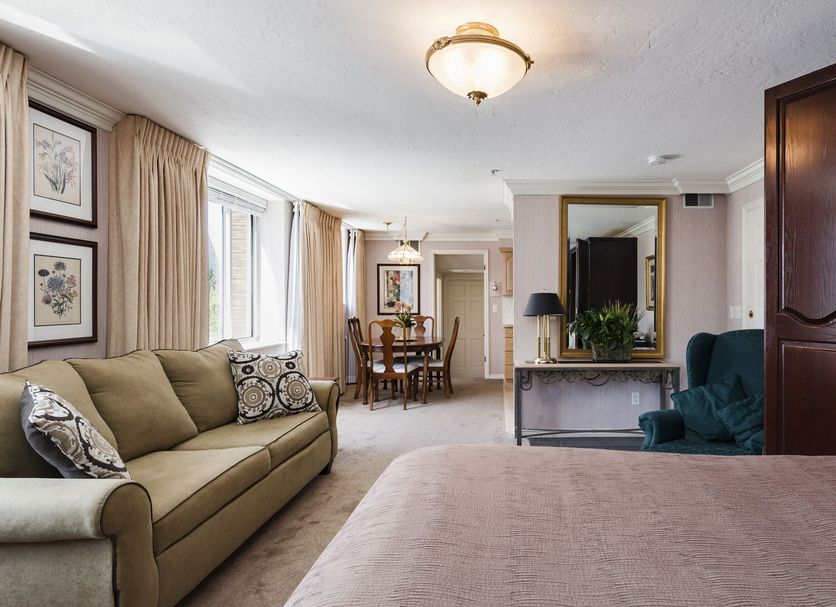 The Kimball at Temple Square guest suite in Salt Lake City with sofa, dining area, and large mirror