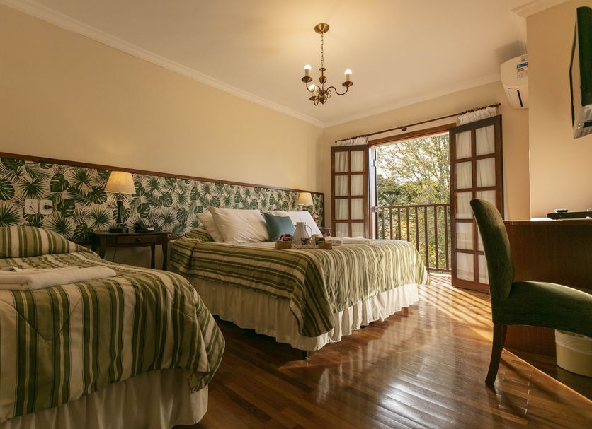 Pousada das Hortensias room in Campos do Jordão with two striped beds, balcony doors and garden view