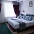 Rohat Hotel Dushanbe guest room with two beds, window curtains, and wall-mounted lights