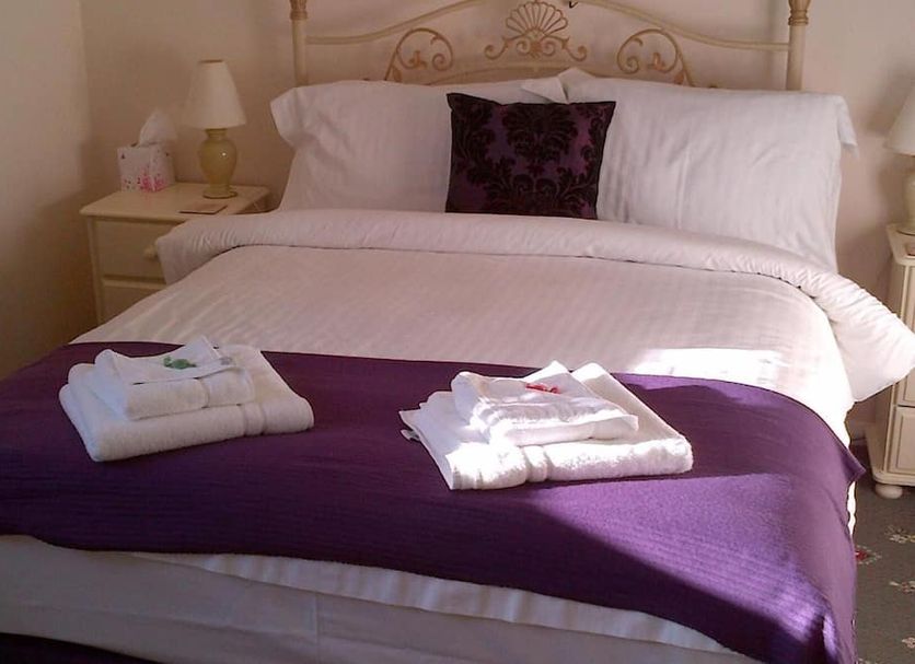 Grove House Hotel, Woodbridge: bedroom with a white bed, purple throw, folded towels, and bedside tables