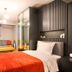 Taks-Inn Suites Istanbul guest room with orange bedspread, sofa, and mirrored wardrobe