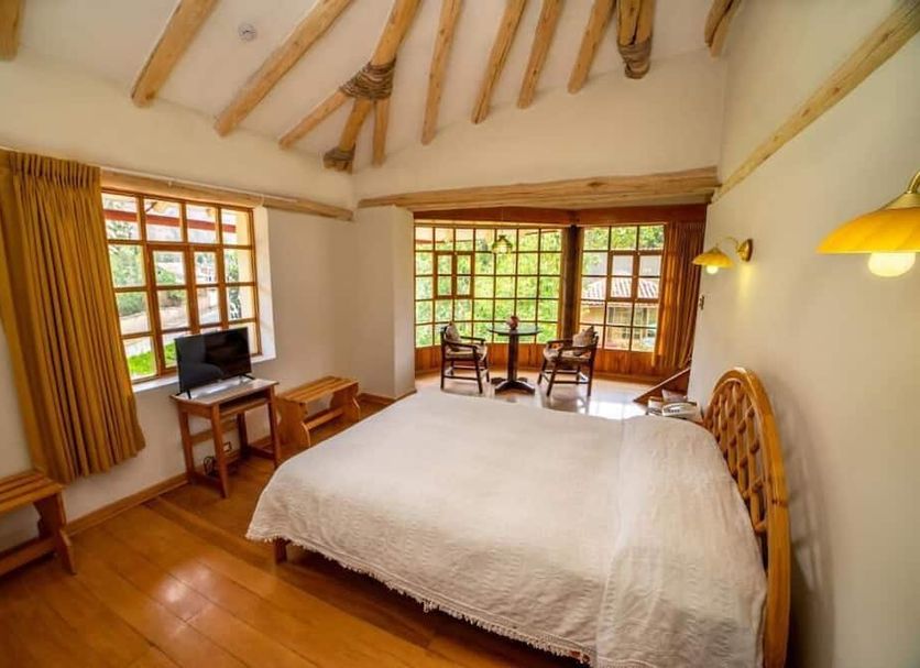 Iorana Hotel Urubamba bedroom in Urubamba with wood-beamed ceiling, large windows, and valley views