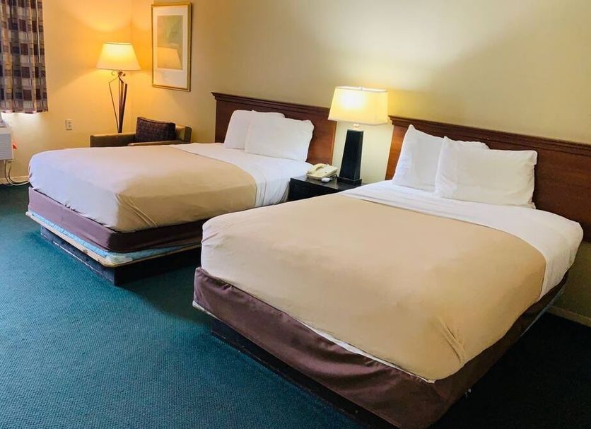 Americas Inn Webster City guest room with two double beds, lamps, and teal carpet