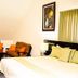 Elite Hotel Port Au Prince guest room with bed, seating area, and curtains