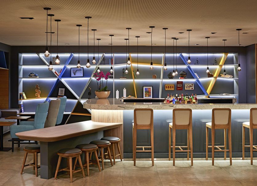 Novotel Campo Grande bar and lounge with illuminated shelves, high stools, and seating area in Campo Grande