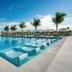 Hotel Riu Latino in Cancún: large outdoor pool with palm trees and oceanfront loungers
