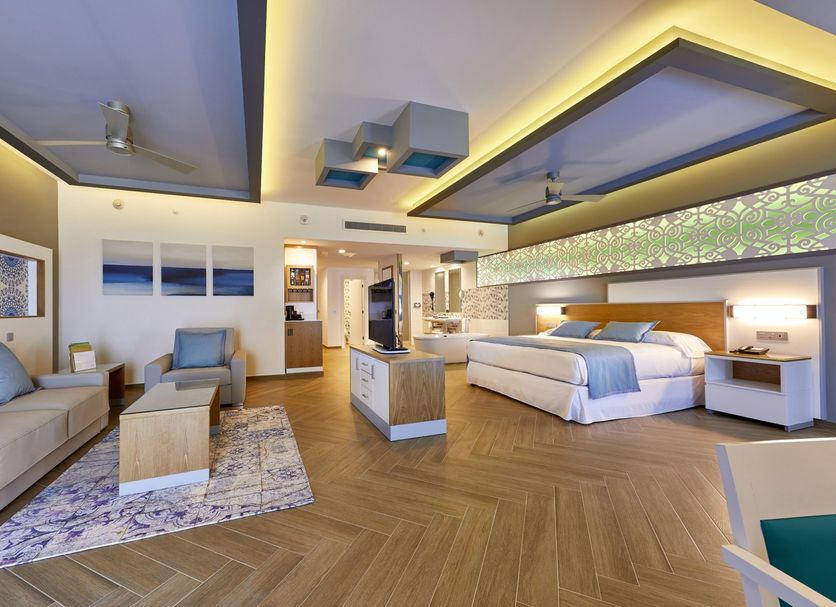 Riu Palace Costa Mujeres in Cancún, spacious guest room with king bed, sofa seating and modern lighting