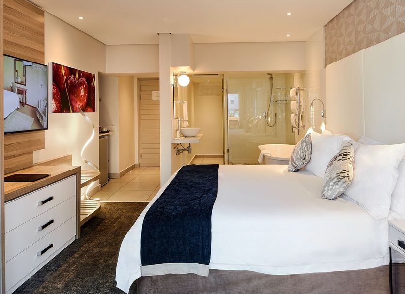 First Group Riviera Suites in Cape Town guest room with king bed, TV, and bathroom view