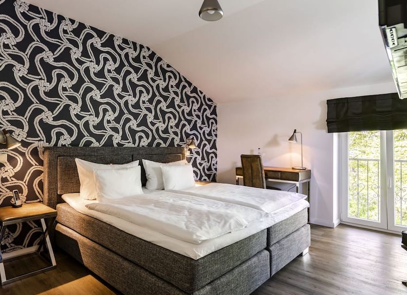 Hotel Ulmenhof & Spa in Bredstedt: modern guest room with double bed, desk and balcony doors