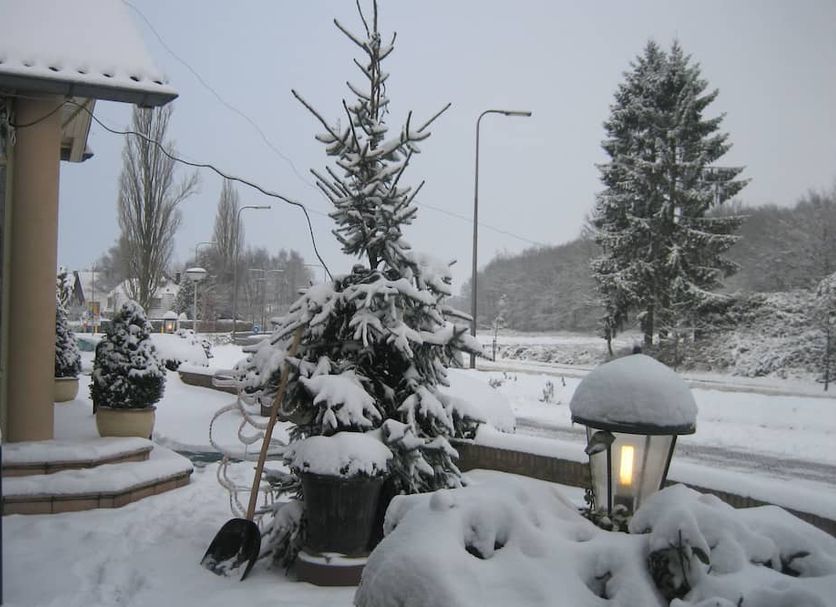 Hotel Het Landhuis in Oldenzaal with snow-covered entrance, evergreen trees and roadside view