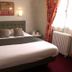 Hotel Le Canada in Hermanville-sur-Mer bedroom with double bed, wall lights and window with curtains