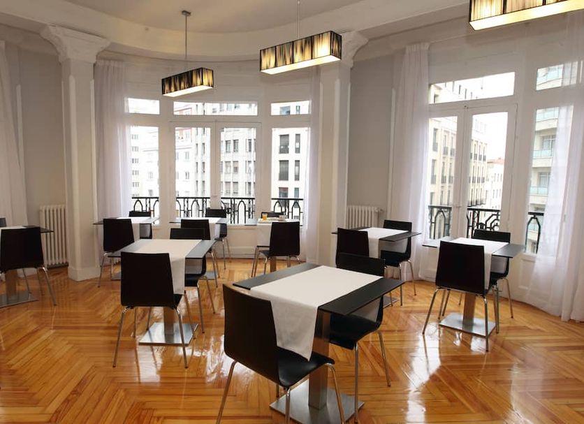 El Rincón de Gran Vía in Madrid lounge with tables, chairs and tall windows overlooking the street