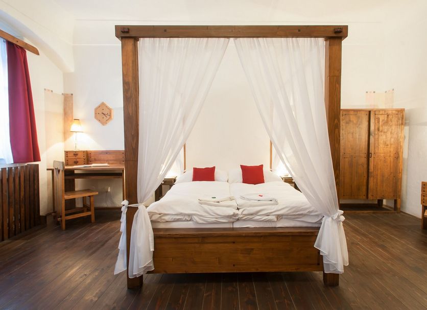 Hotel U Malého Vitka in Český Krumlov, four-poster bed with white curtains in a simple guest room