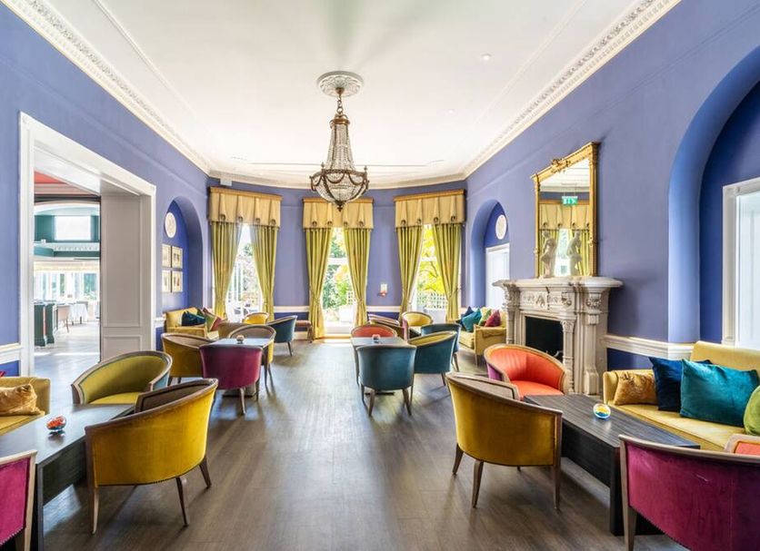 The Bromley Court Hotel in Bromley lounge with blue walls, arched windows, chandelier and colorful seating