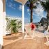 Hotel Ristorante Mediterraneo Faro terrace with lounge chairs, palm trees, and sea and mountain views in San Vito Lo Capo
