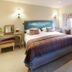 Greenhills Country Hotel in Saint Peter bedroom with teal headboard, plaid throw, vanity, armchair and window seat