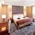 Colosseum Hotel in Mórahalom bedroom with a double bed, lamps, desk, armchair and large window