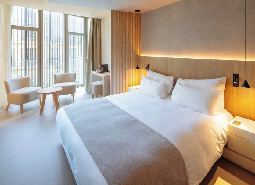 Hotel Arconte Barcelona guest room with king bed, floor-to-ceiling windows, and seating area