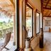 The Colonial at Jaguar Reef in Hopkins guest room with wooden bed, orange walls, and balcony view