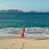 Green Roof Inn in Carriacou beach scene with turquoise water, distant islands, and a couple by the shore