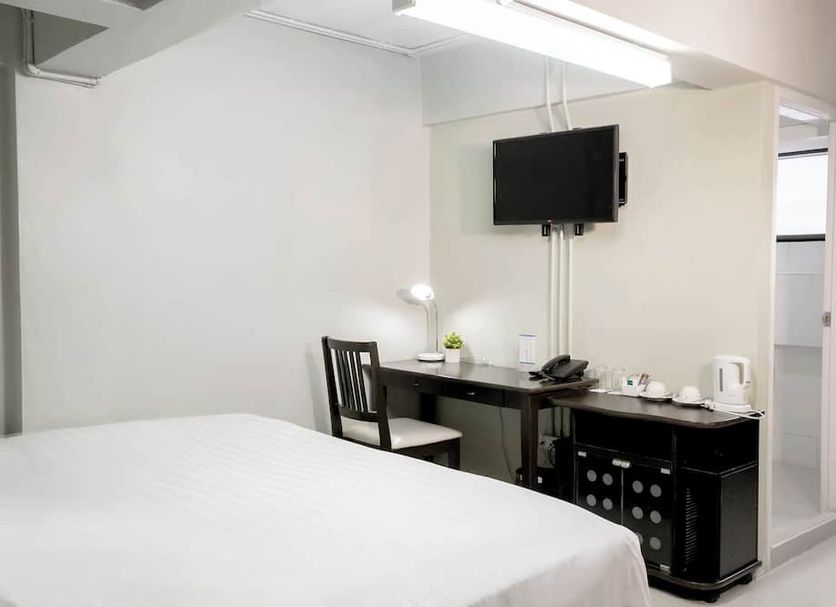 Annex Lumpini Bangkok room with bed, desk, wall-mounted TV, and mini fridge in Bangkok