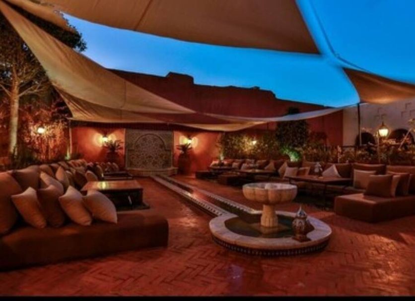 Riad Adahab in Oujda courtyard lounge with seating, fountain and shade sails at dusk