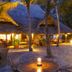 Baobab Beach Resort & Spa in Ukunda, palm-lined patio with thatched dining area at dusk