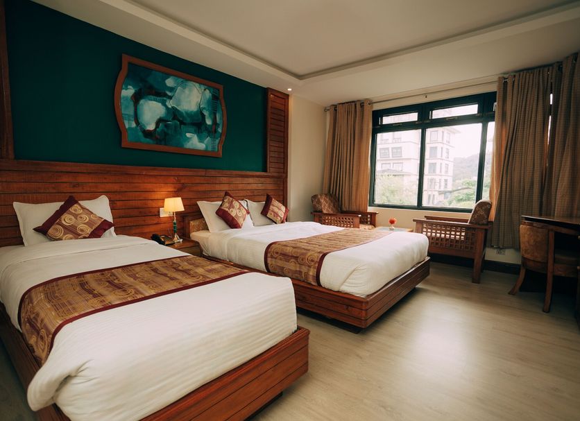Hotel Tulsi Pokhara guest room with two beds, wood-paneled wall and large window