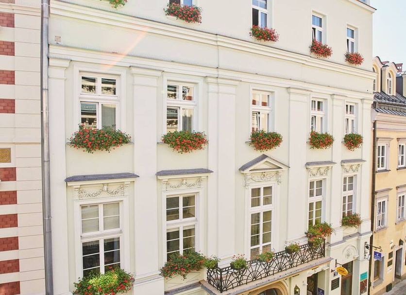 Unikat Guest Rooms in Krakow, exterior of a white building with flower boxes on windows