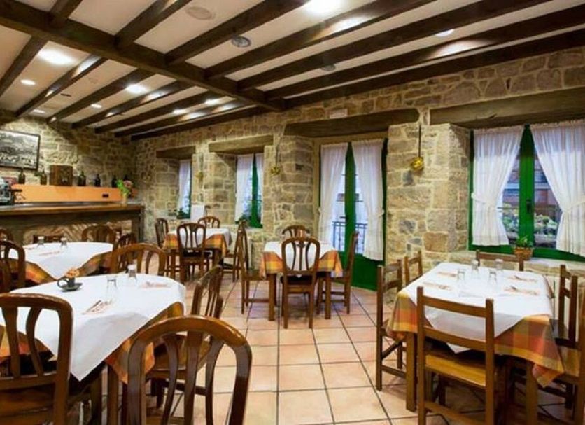 Hotel Villa de Cabrales in Las Arenas dining room with stone walls, wood beams and set tables