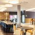 Staycity Aparthotels Heidelberg dining area with long table, bar seating, and warm modern lighting