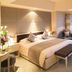 Hengshan Garden Hotel Shanghai guest room with king bed, bench, armchair and city view window
