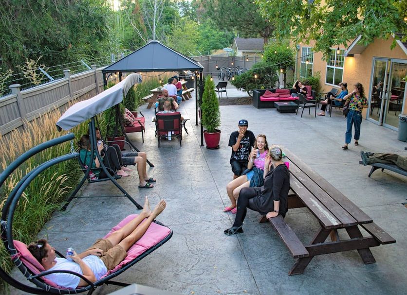Hi Kelowna Hostel patio with guests lounging, picnic tables, and garden seating in Kelowna