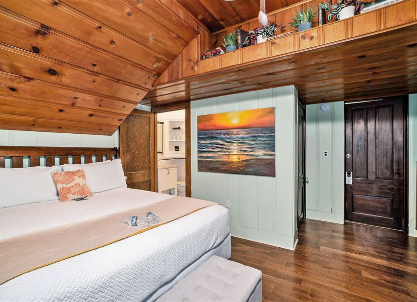 Historic Hotel Nichols South Haven guest room with wood-paneled vaulted ceiling and ocean sunset wall art