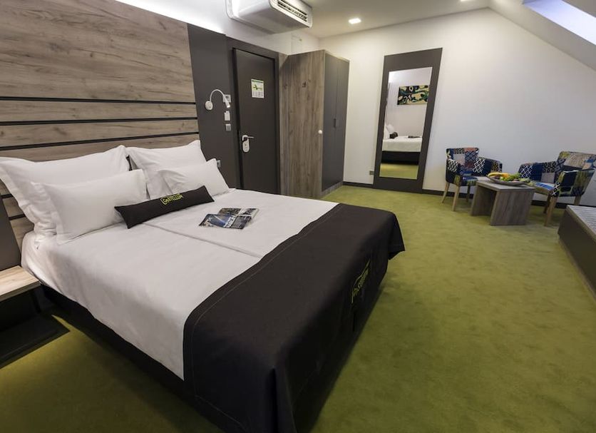 Hotel Castellum in Čakovec guest room with king bed, mirror, wardrobe, and seating area