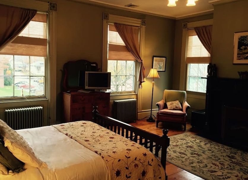 The Borland House Inn in Montgomery bedroom with four-poster bed, windows, armchair, and floor lamp